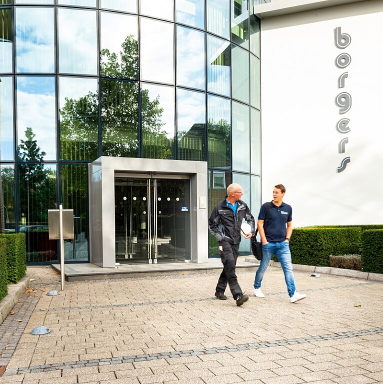 zwei Mitarbeiter der Borgers GmbH laufen aus dem Verwaltungsgebäude