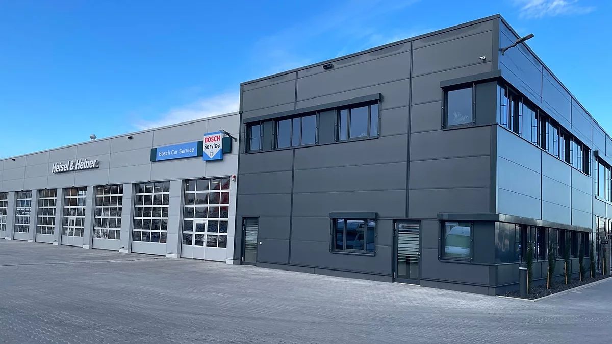 Autohaus mit dunkelgrauem Verwaltungsgebäude und angrenzender Werkstatthalle für Nutzfahrzeuge