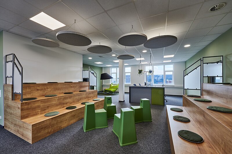 Innenansicht eines modernen Bürogebäudes mit Amphitheater-Sitzplätzen, Loungebereich und Arbeitsplätzen