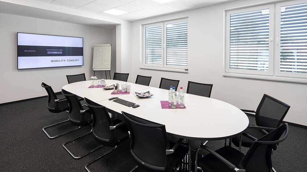 Besprechungsraum mit langem Tisch und Medientechnik im Verwaltungsbereich