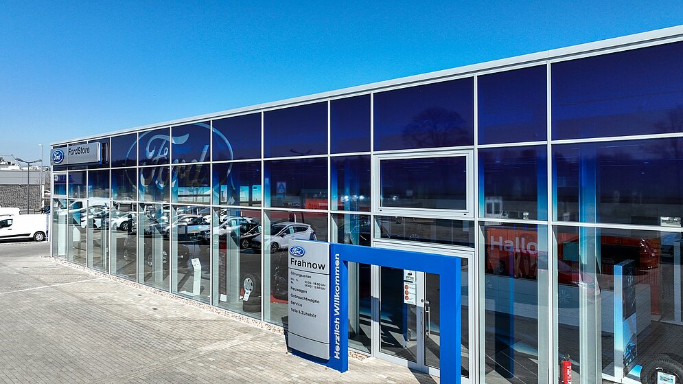 Detailansicht der blauen Glasfassade des schlüsselfertigen Ford Autohauses mit Eingangsbereich