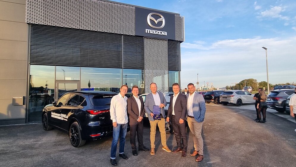 Fünf Personen vor Mazda Autohaus mit goldenem Schlüssel