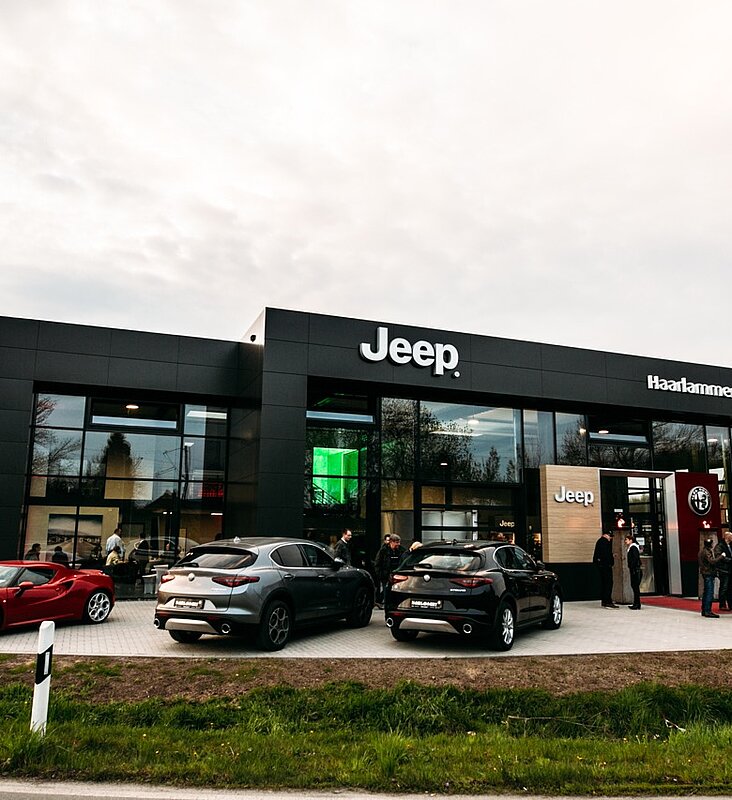 Frontansicht des Jeep Autohauses mit schwarzer Fassade und Glasfront von der Straße