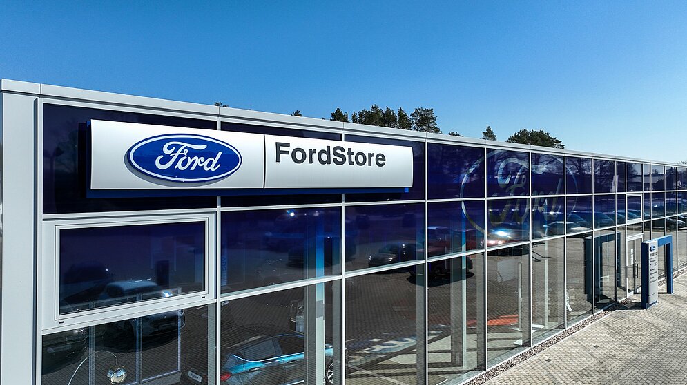Fassadendetail des Ford Stores mit blauer Verblendung und Logo über der Glasfront