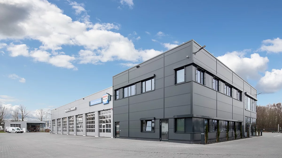 Bürogebäude aus grauen Metallpaneelen mit angrenzender, überdachter Fläche für Nutzfahrzeuge