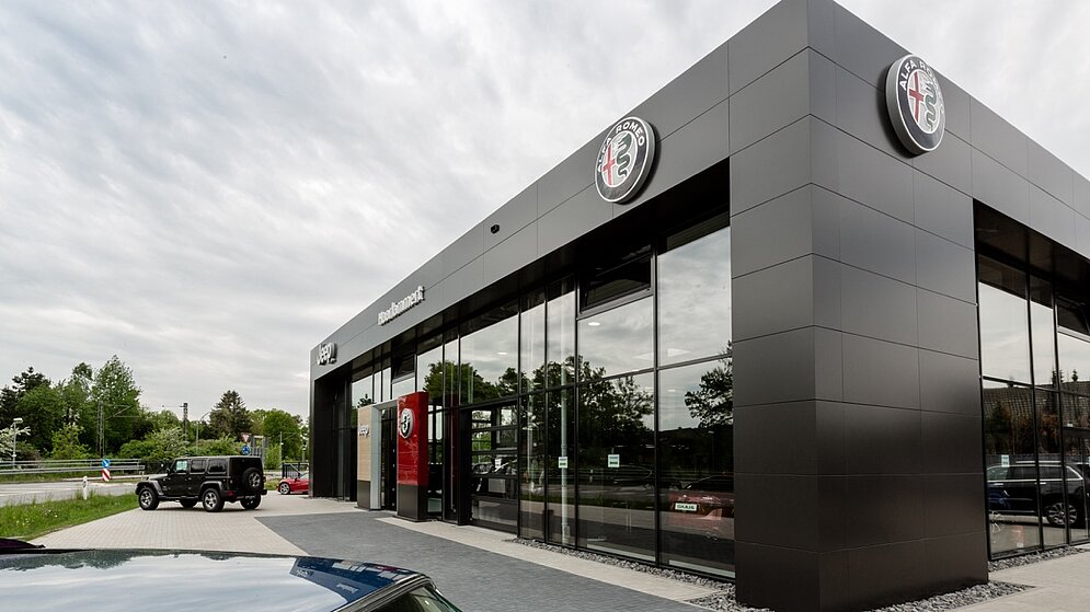 Moderne Fassadengestaltung des Alfa Romeo Autohauses mit dunkler Verkleidung und Logo