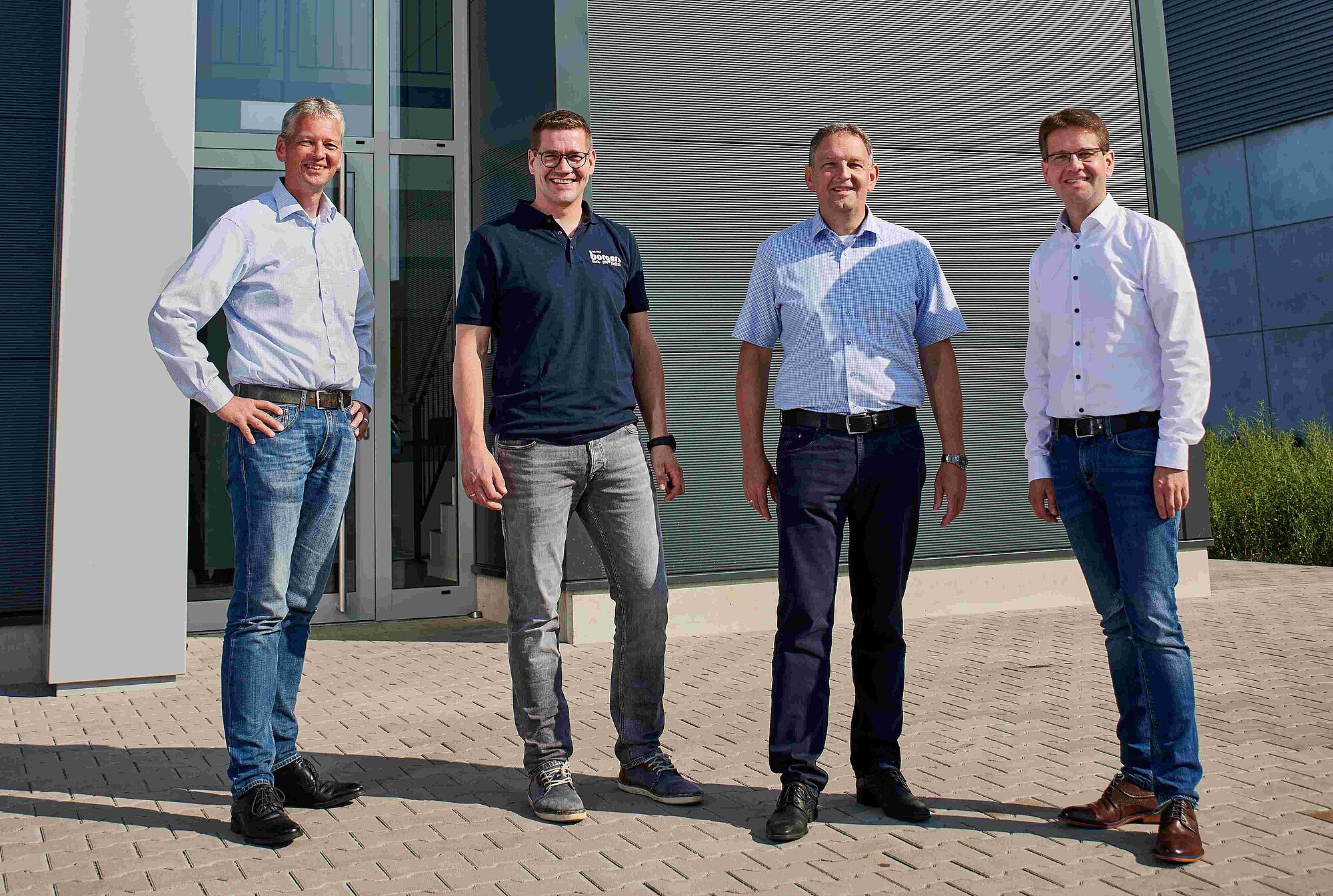 Vier Herren vor einem Betriebsgebäude