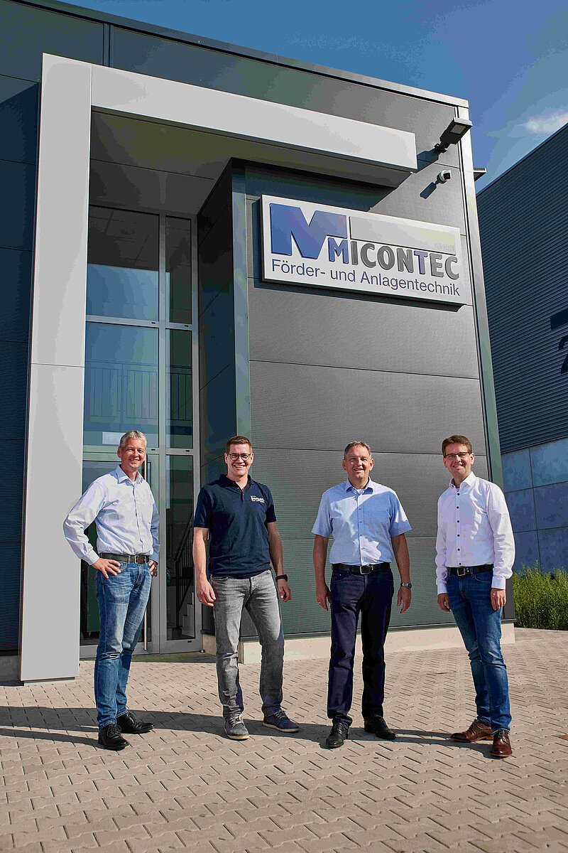 Vier Herren vor einem Betriebsgebäude