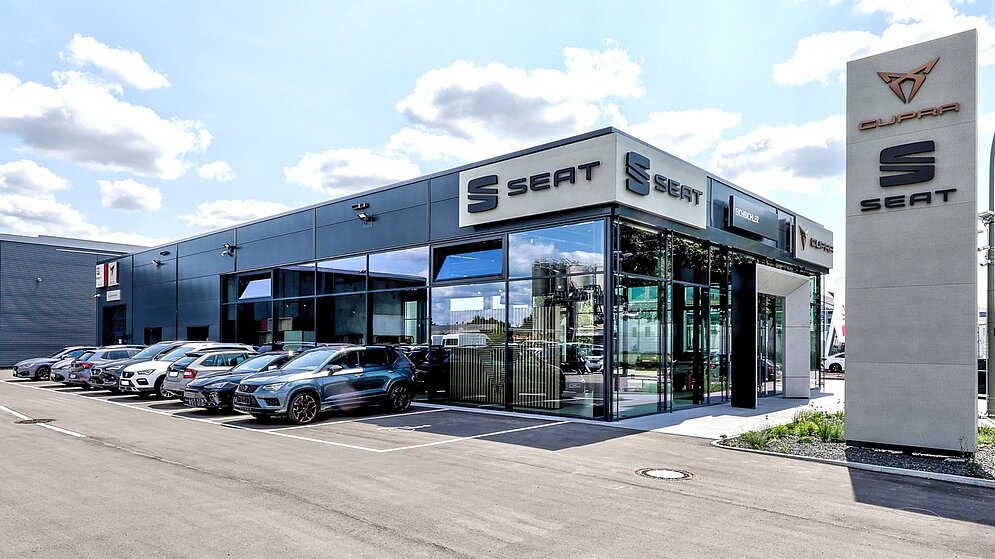 Straßenansicht des schlüsselfertigen Autohauses mit Fahrzeugausstellung und Werbepylonen