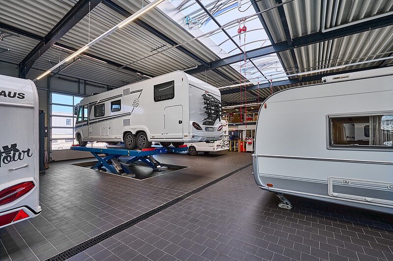 Innenansicht einer großen, sauberen Werkstatthalle für Wohnmobile und Wohnwagen