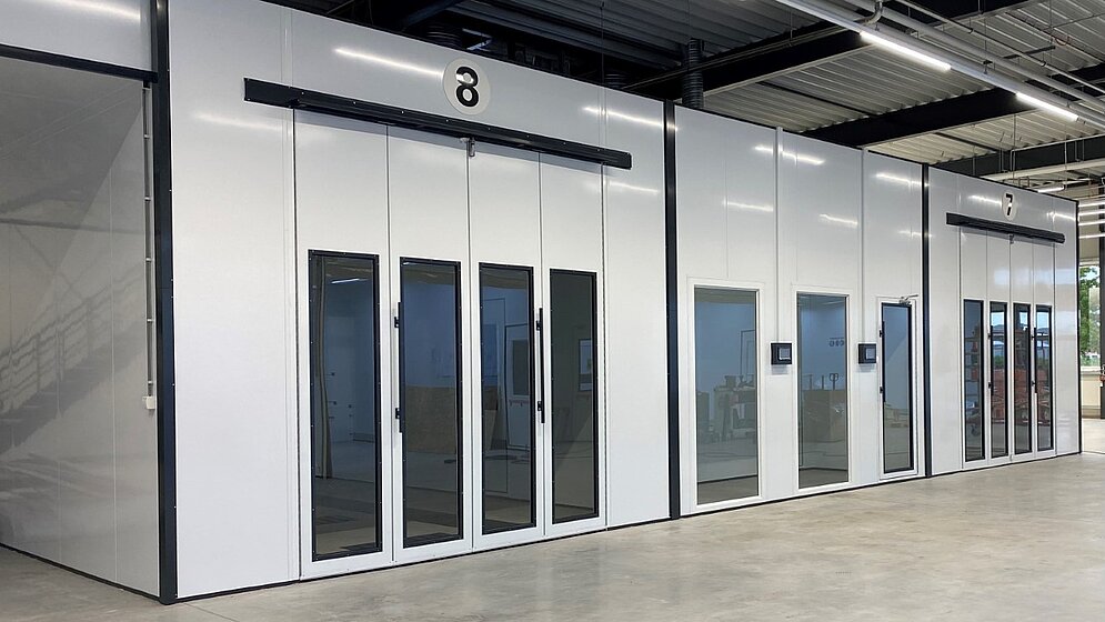 Weiße, moderne Lackierkabinen in einer geräumigen Hallenwerkstatt