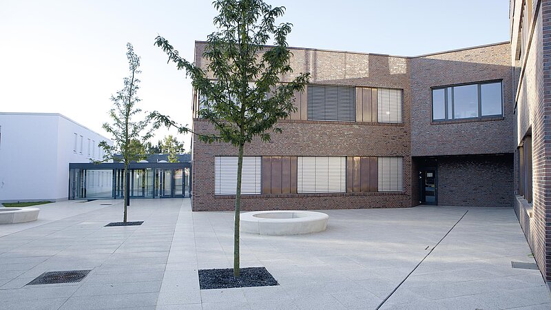 Innenhof eines modernen Verwaltungsgebäudes, umgeben von Neubauten in Klinker- und Ziegeloptik