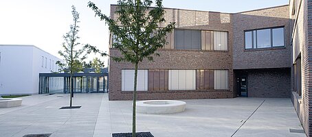 Innenhof eines modernen Verwaltungsgebäudes, umgeben von Neubauten in Klinker- und Ziegeloptik