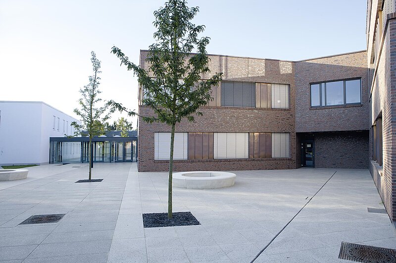 Innenhof eines modernen Verwaltungsgebäudes, umgeben von Neubauten in Klinker- und Ziegeloptik