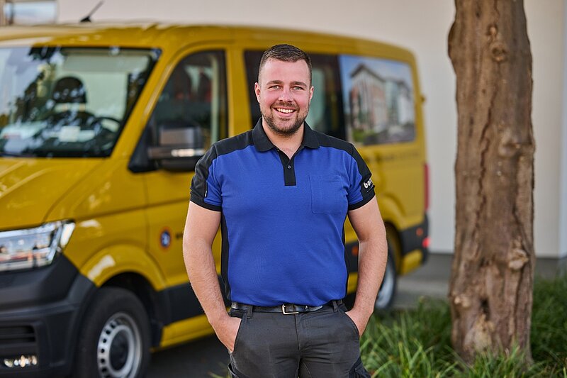 Borgers Mitarbeiter Joshua Könning steht vor gelbem Borgers Bulli