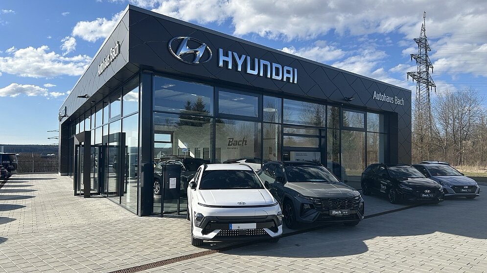 Außenansicht des Gewerbebaus mit Fahrzeugpräsentation vor der Glasfassade