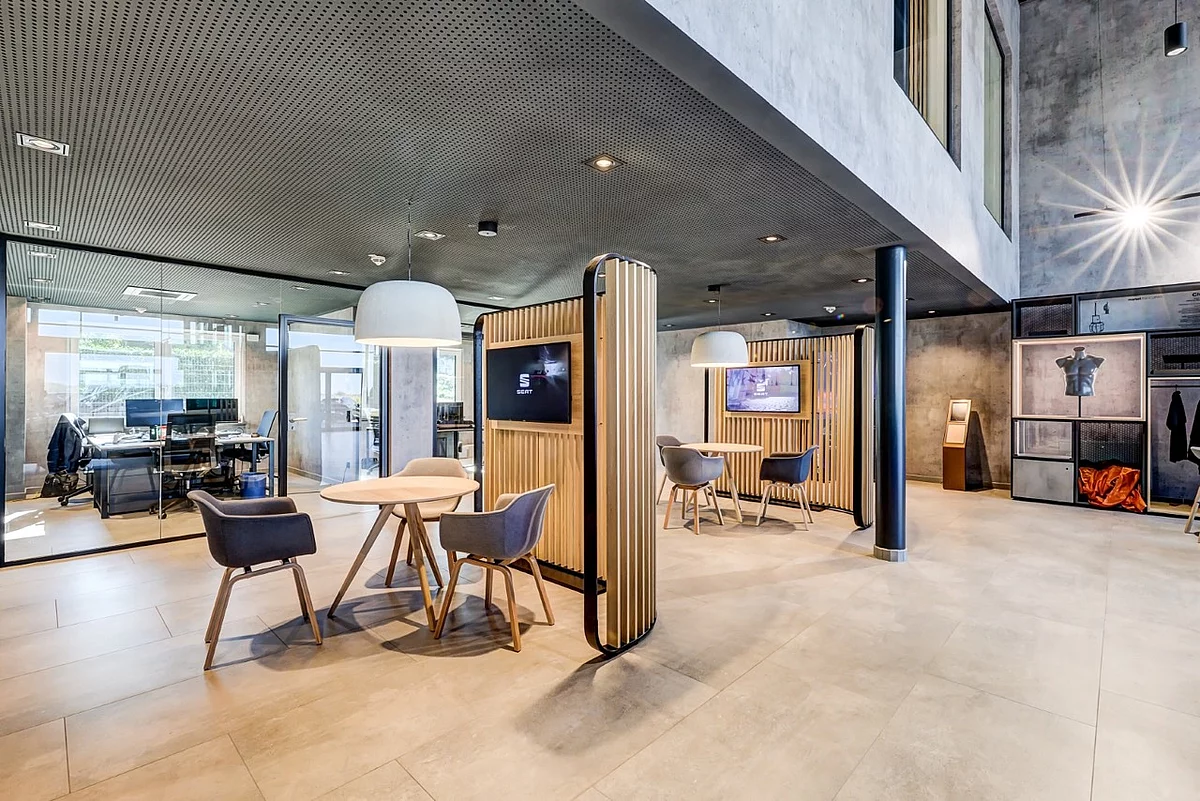 Open-Space-Büro eines Autohauses mit Sitzecken, Einbaumöbeln aus Holz und einer Decke mit Akustikverkleidung