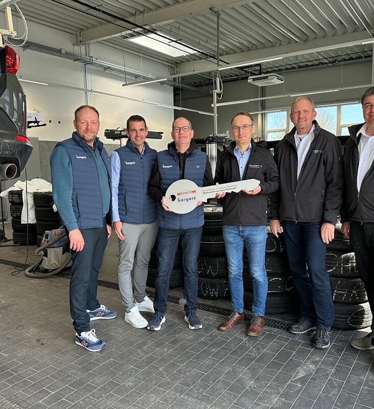 sechs Personen in einer Werkstatt mit Schlüssel in der Hand