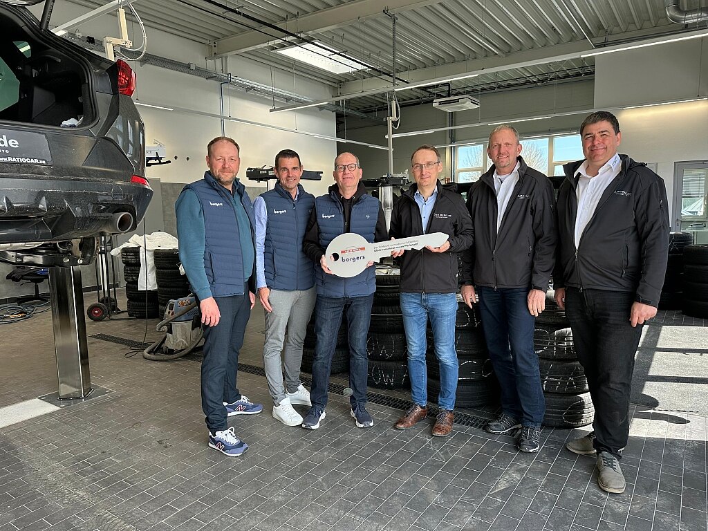 sechs Personen in einer Werkstatt mit Schlüssel in der Hand