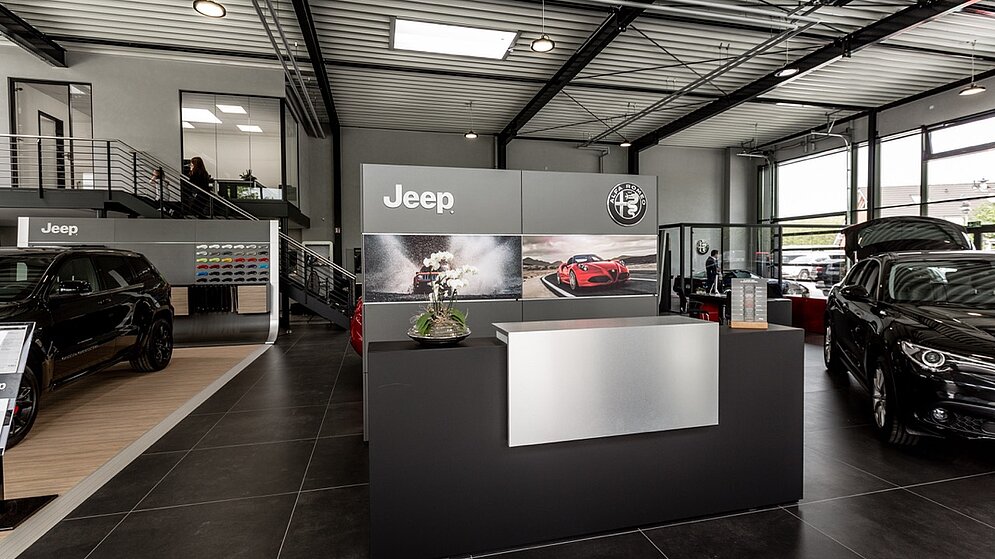 Empfangsbereich mit Theke und Jeep-Branding im Autohaus-Innenraum