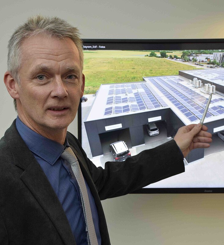 Mann mit Krawatte steht vor einem Bildschirm