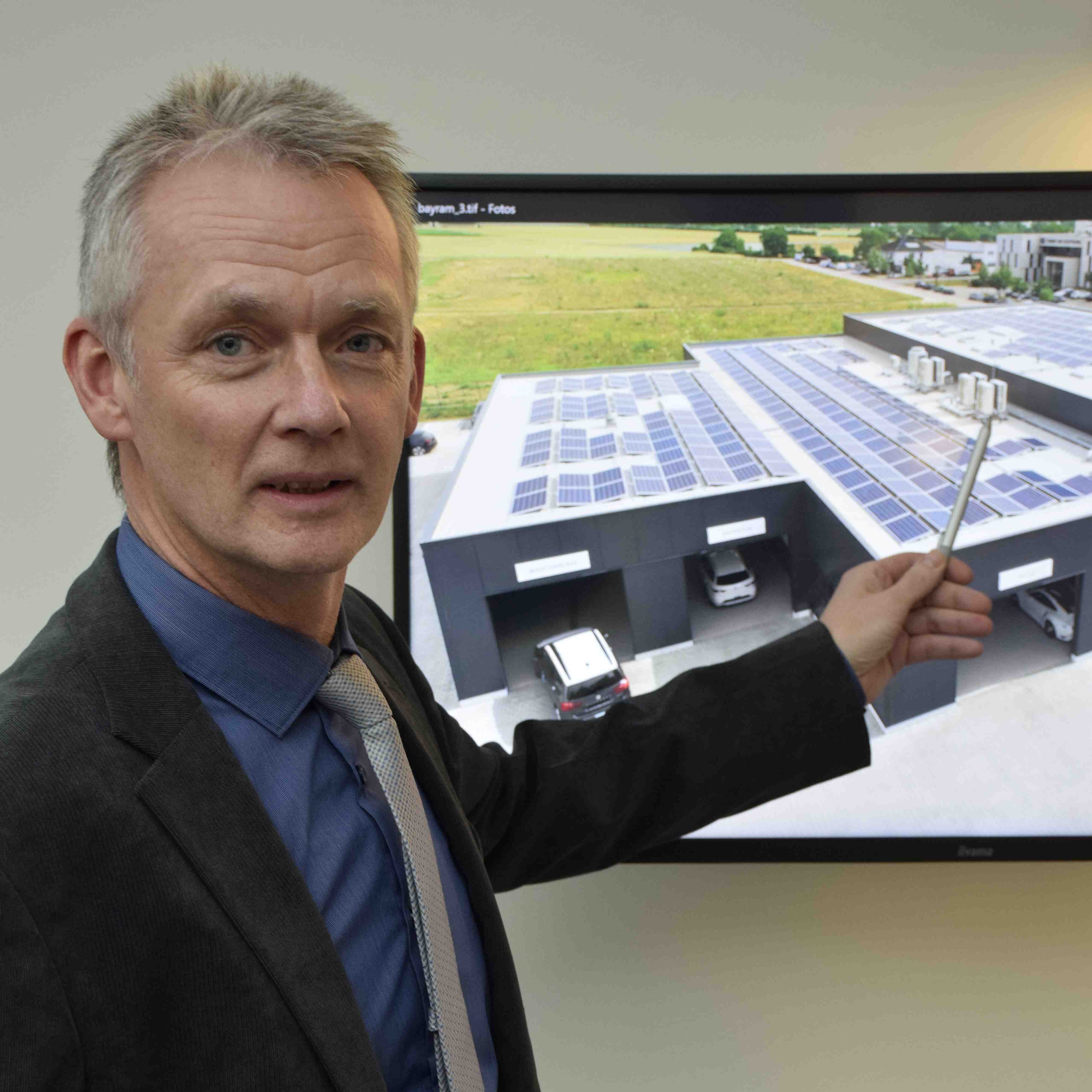 Mann mit Krawatte steht vor einem Bildschirm