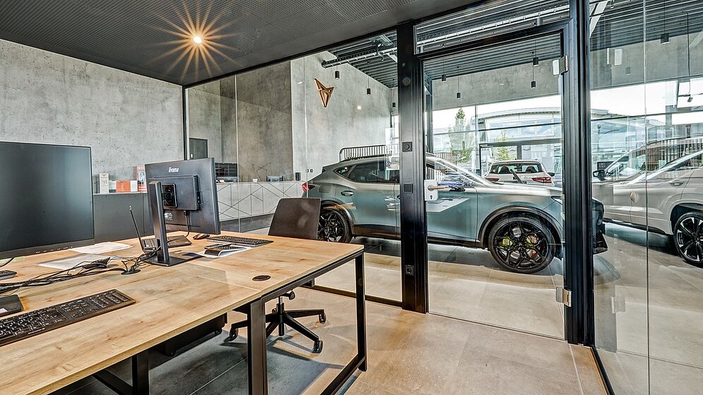 Verglastes Verkaufsbüro im Showroom mit modernem Innenausbau und Blick in die Halle