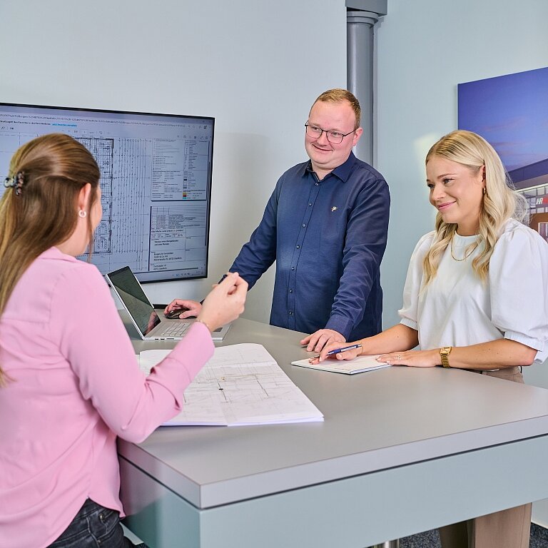 Vier Mitarbeiter der Borgers GmbH unterhalten sich. Es ist ein Bildschirm mit Plänen im Hintergrund zu sehen.
