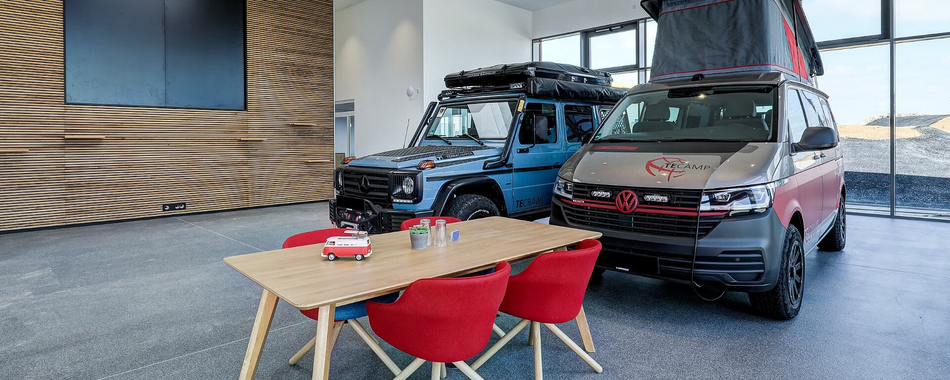 Moderner Showroom mit Camper-Van und Jeep und Tisch für Kundengespräche