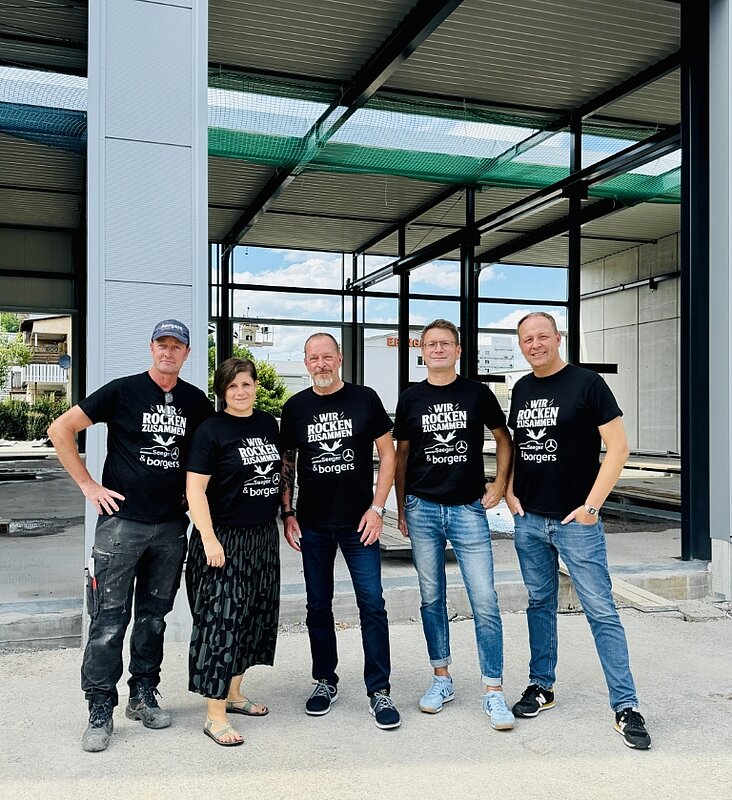Fünf Personen mit schwarzen T-Shirts auf einer Baustelle