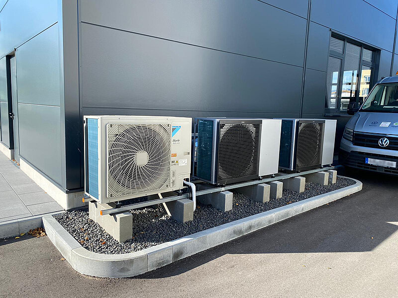 drei Wärmepumpen vor einem Industriegebäude