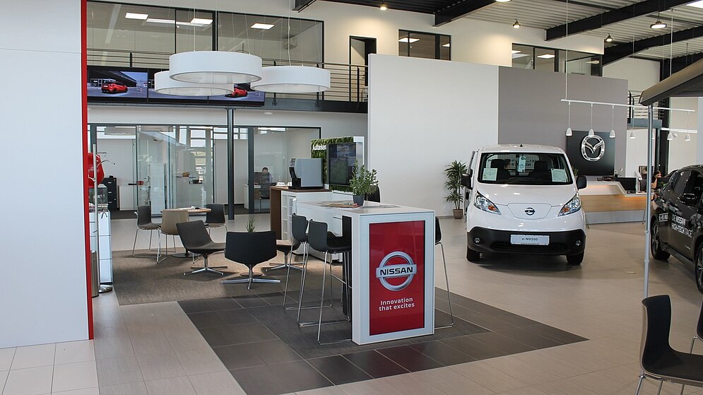 Moderner Verkaufsraum mit Beratungsinsel und Fahrzeugausstellung im schlüsselfertigen Bau