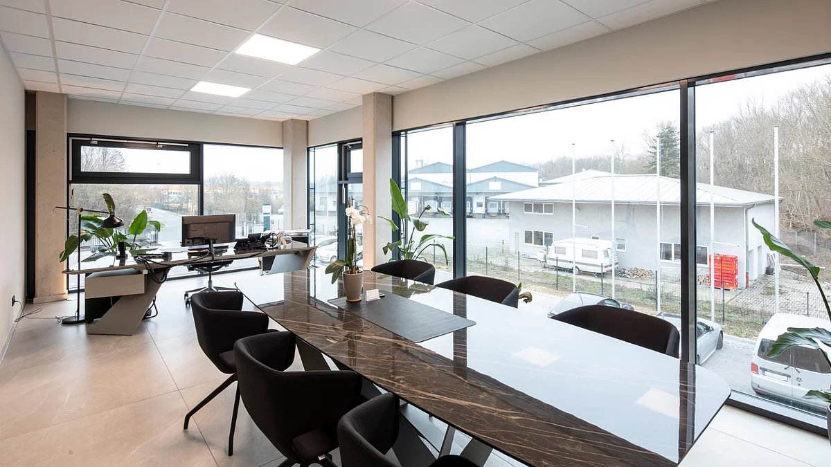 Innenansicht eines modernen Büros mit langen Schreibtischen und einer großen Fensterfront