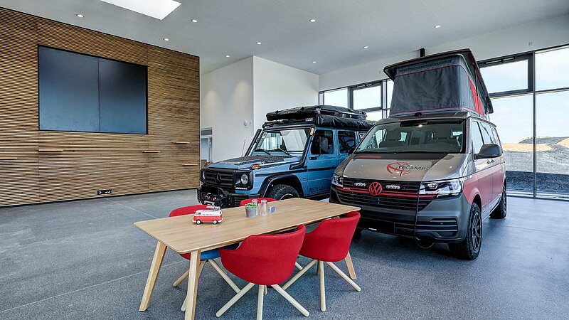 Moderner Showroom mit Camper-Van und Jeep und Tisch für Kundengespräche