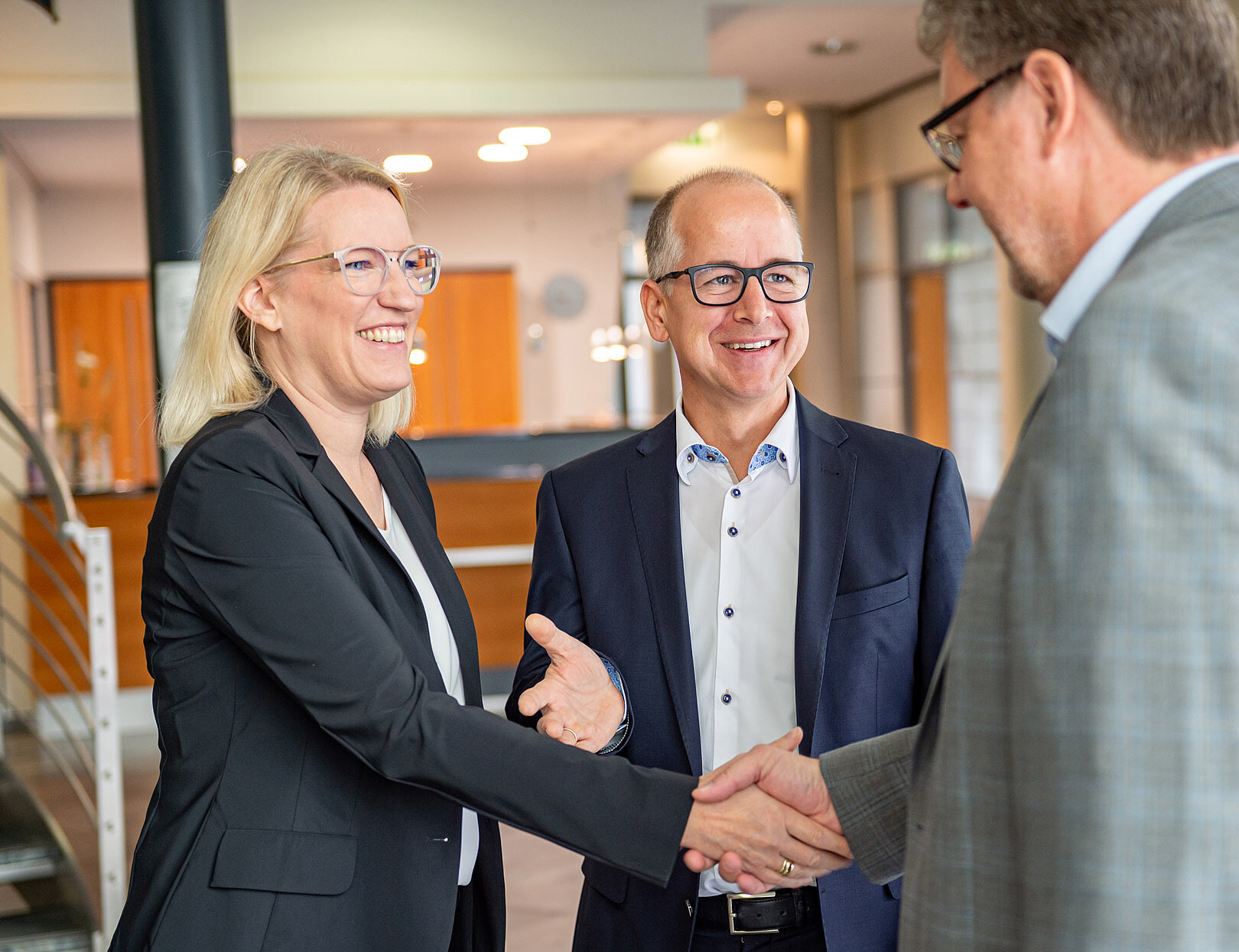 Die Geschäftsleitung reicht einem Herrn partnerschaftlich die Hand