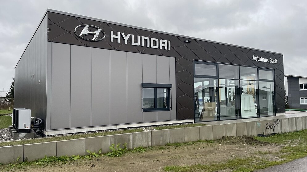 Seitenansicht des schlüsselfertigen Hyundai Autohauses mit grauer Fassade und Glasfront
