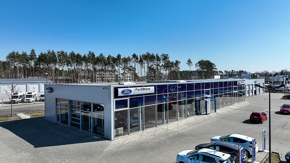 Frontansicht des Autohauses mit großflächiger Verglasung und Ford-Branding bei Sonnenschein