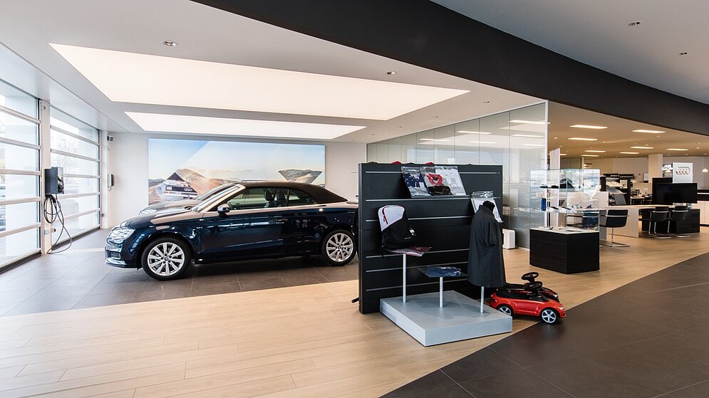 Empfangsbereich des Autohauses mit Infotheke, Fahrzeugausstellung und hochwertigem Innenausbau