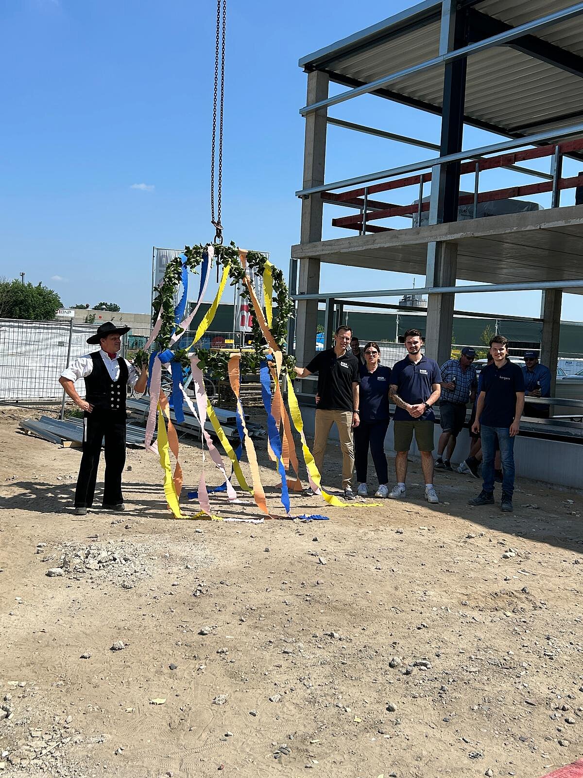 Personen auf einer Baustelle mit Richtkranz