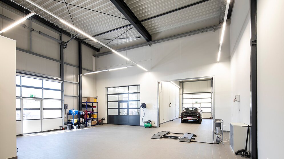 Helle Fahrzeugübergabehalle mit Sektionaltor und Industrieboden