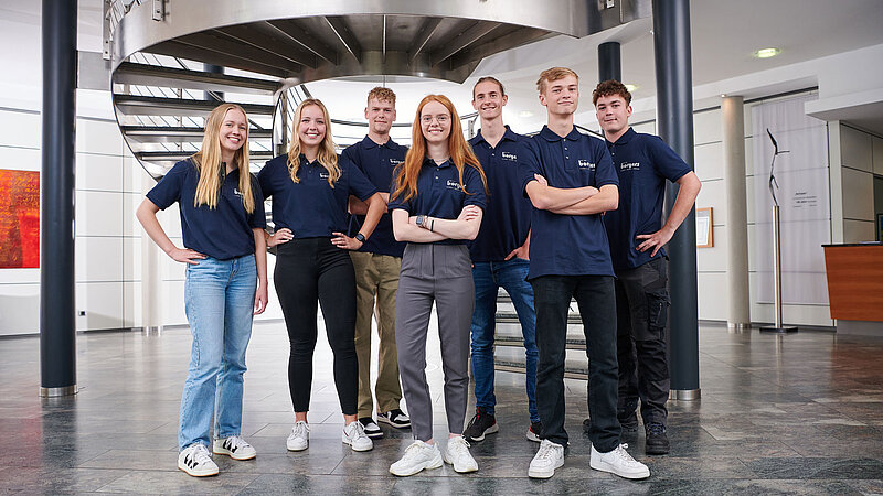Teamfoto von sieben jungen Azubis der Borgers GmbH in blauen T-Shirts im Büro