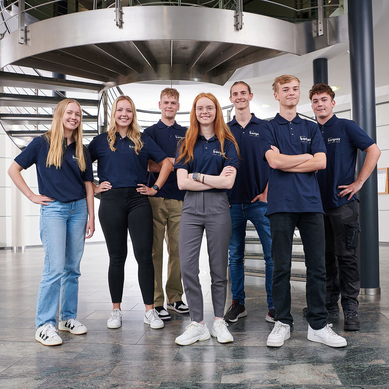 Teamfoto von sieben jungen Azubis der Borgers GmbH in blauen T-Shirts im Büro