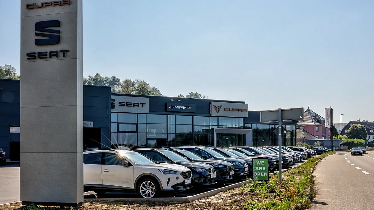 Außenansicht eines modernen Autohauses mit Verkaufsbereich und vielen Neuwagen auf dem Gelände