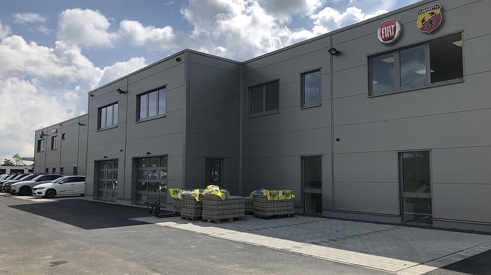 Außenansicht der grauen Gebäudefassade mit Sektionaltoren und Abarth-Logo