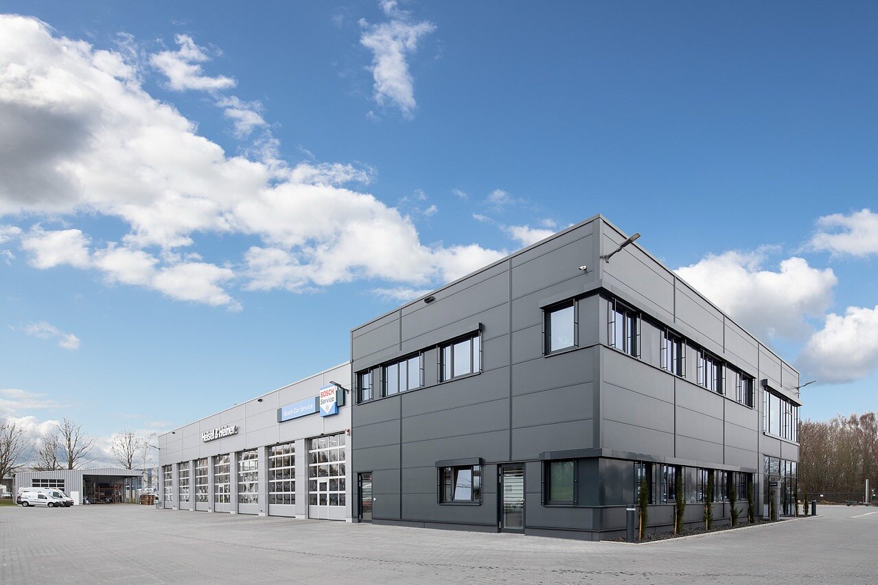 Bürogebäude aus grauen Metallpaneelen mit angrenzender, überdachter Fläche für Nutzfahrzeuge