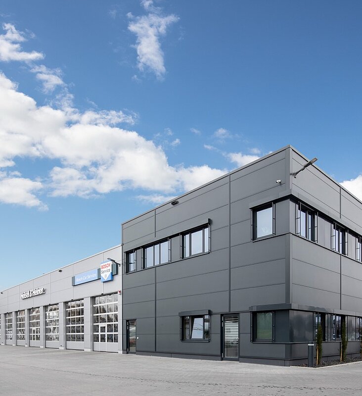 Bürogebäude aus grauen Metallpaneelen mit angrenzender, überdachter Fläche für Nutzfahrzeuge