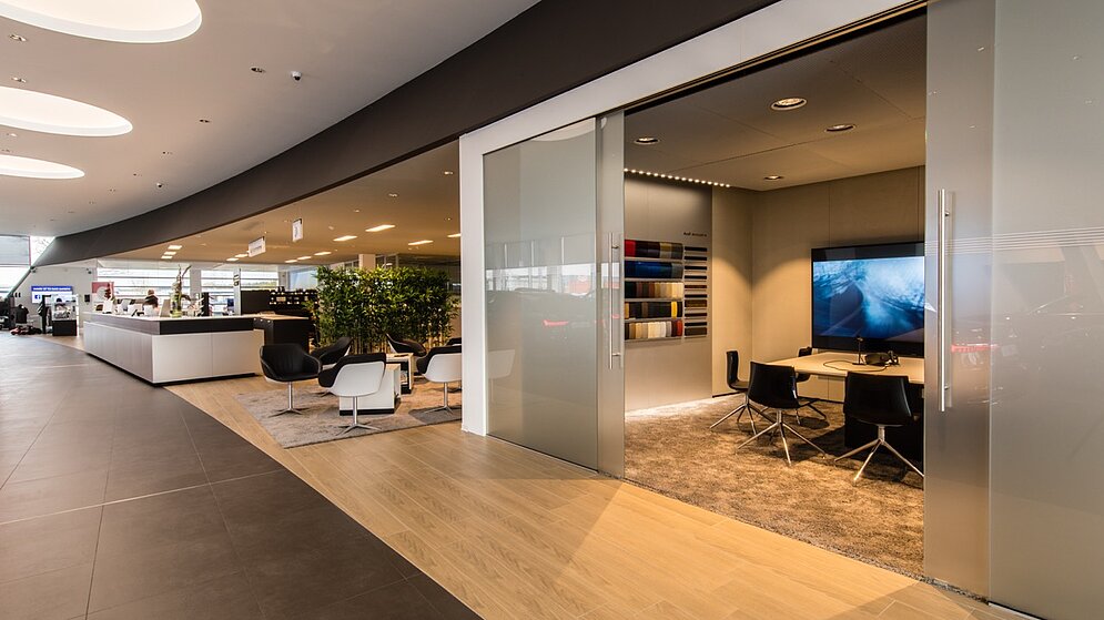 Moderne Kundenlounge mit geschwungener Deckenkonstruktion und verglastem Beratungsraum