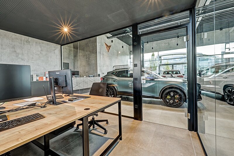Verglastes Verkaufsbüro im Showroom mit modernem Innenausbau und Blick in die Halle