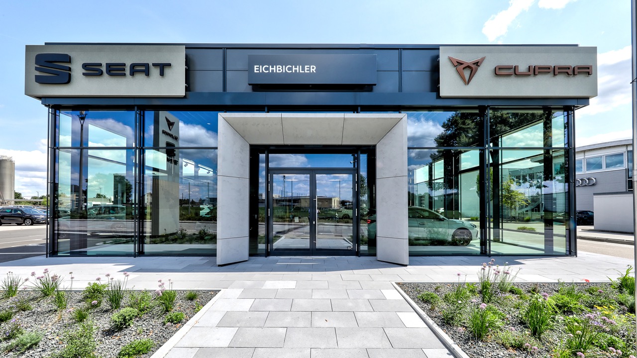 Frontansicht des schlüsselfertigen Seat und Cupra Autohauses Eichbichler mit Glasfassade und Eingang