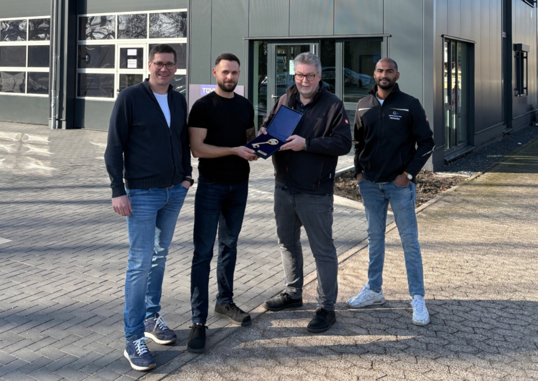 vier Personen vor einem Gebäude mit einem goldenen Schlüssel in der Hand